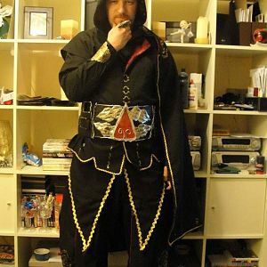 Front view.
Beaked Hood, shirt with red stripe sleeves, Cape w/fur trim, Gold bracer, Lined waiscoat Jacket (No sleeves), Various other flowing compo