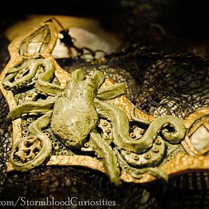 Solid sculpted "wearable art" piece of a nautical theme. An octopus climbing the side of a barnacle-covered vessel while holding a human skull.