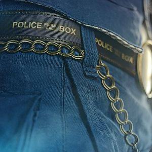 Detail of the belt with printed "Police Public Call Box" ribbon attached to a brown leather belt blank.