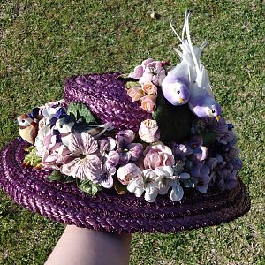 A hand dyed straw hat with velvet flowers and faux birds.