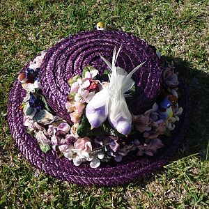 A hand dyed straw hat with velvet flowers and faux birds.