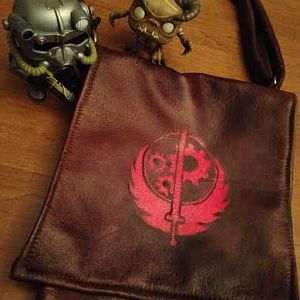 I made a bag to carry my things around in during cons. Made of faux leather, with a black inner lining and an adjustable strap. Spray painted the BoS